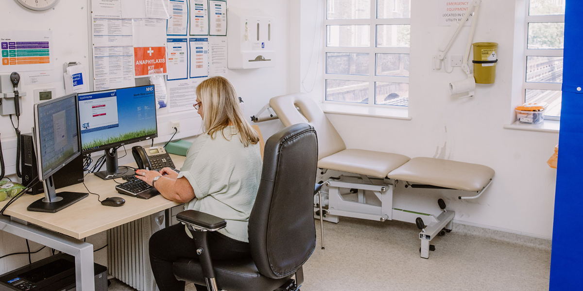Clinician working at laptop in a consultation room